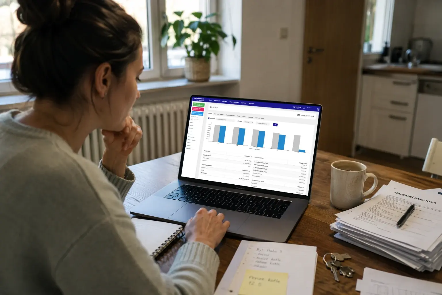 Žena u notebooku se statistikami Repilotu a vytištěnou nájemní smlouvou na stole